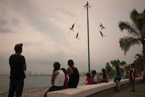 People watch as Papantla Flyers perform on the seafront in the Pacific resort city of Puerto Vallarta, Mexico, Thursday, Oct. 22, 2015. <span class=meta>AP Photo/ Cesar Rodriguez</span>
