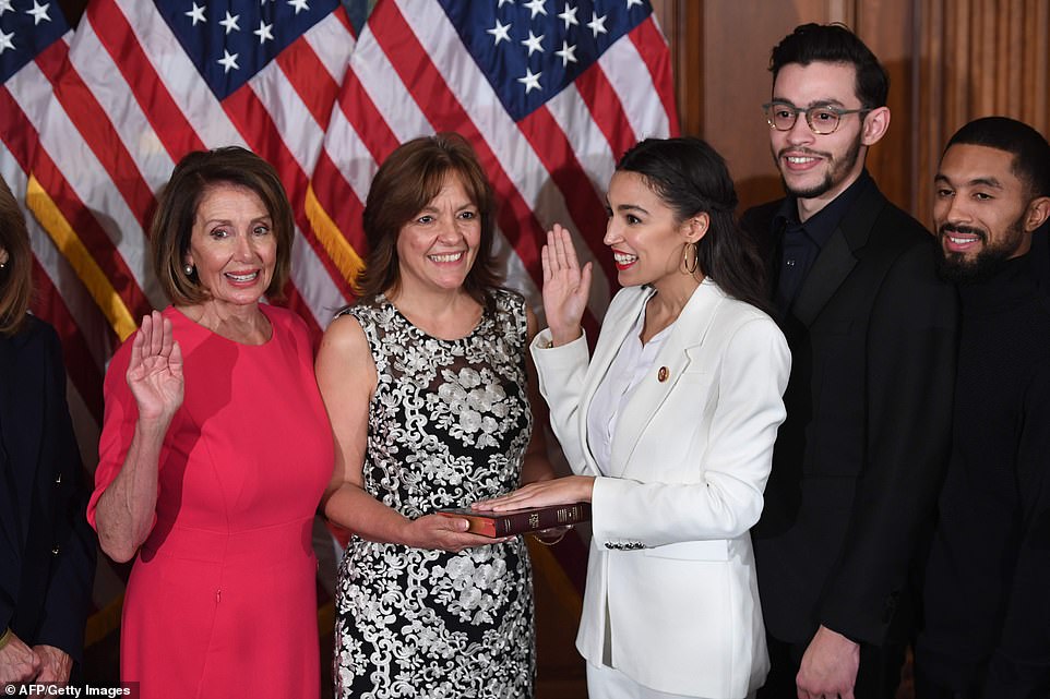 Reason to smile: Alexandria Ocasio-Cortez was sworn in on a copy of the Bible held by her mom and with her brother Gabriel beside her